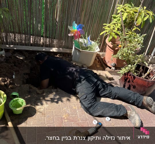 אדם עובד על צינור מים בחצר עם כלי עבודה